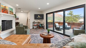 A modern living room with a fireplace, comfortable seating, a flat-screen TV, and a large sliding glass door leading to an outdoor patio. - NEW Redrock Experience Views Firepit Hottub (Sedona)