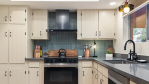 A modern kitchen with light-colored cabinets, a stainless steel oven, and a black range hood. - NEW Redrock Experience Views Firepit Hottub (Sedona)