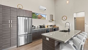 A modern kitchen with a stainless steel refrigerator, a built-in oven, and a microwave. There is a window providing a view of the outdoors. - NEW Moondance Red Rock Retreat Epic Views (Sedona)