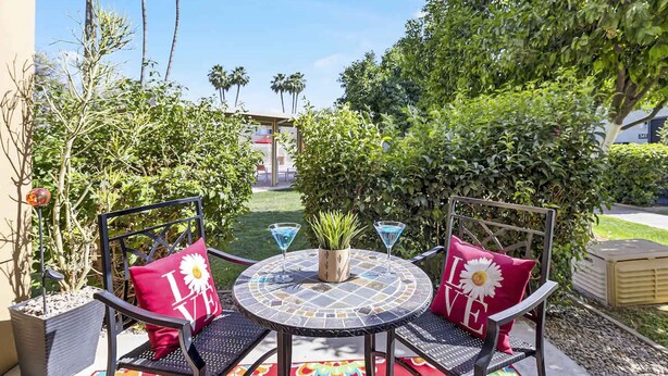 Un patio exterior con dos sillas, una mesa redonda y dos copas de martini.