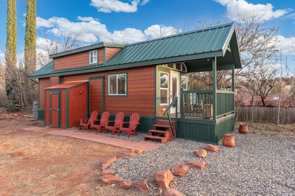 A rustic cabin with a porch, wooden exterior, and a gravel driveway. - NEW Moondance Majestic Mini Cabin Cathedral Rock (Sedona)