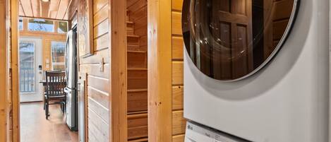 A laundry room with two stacked washing machines, wooden walls, and a wooden floor.