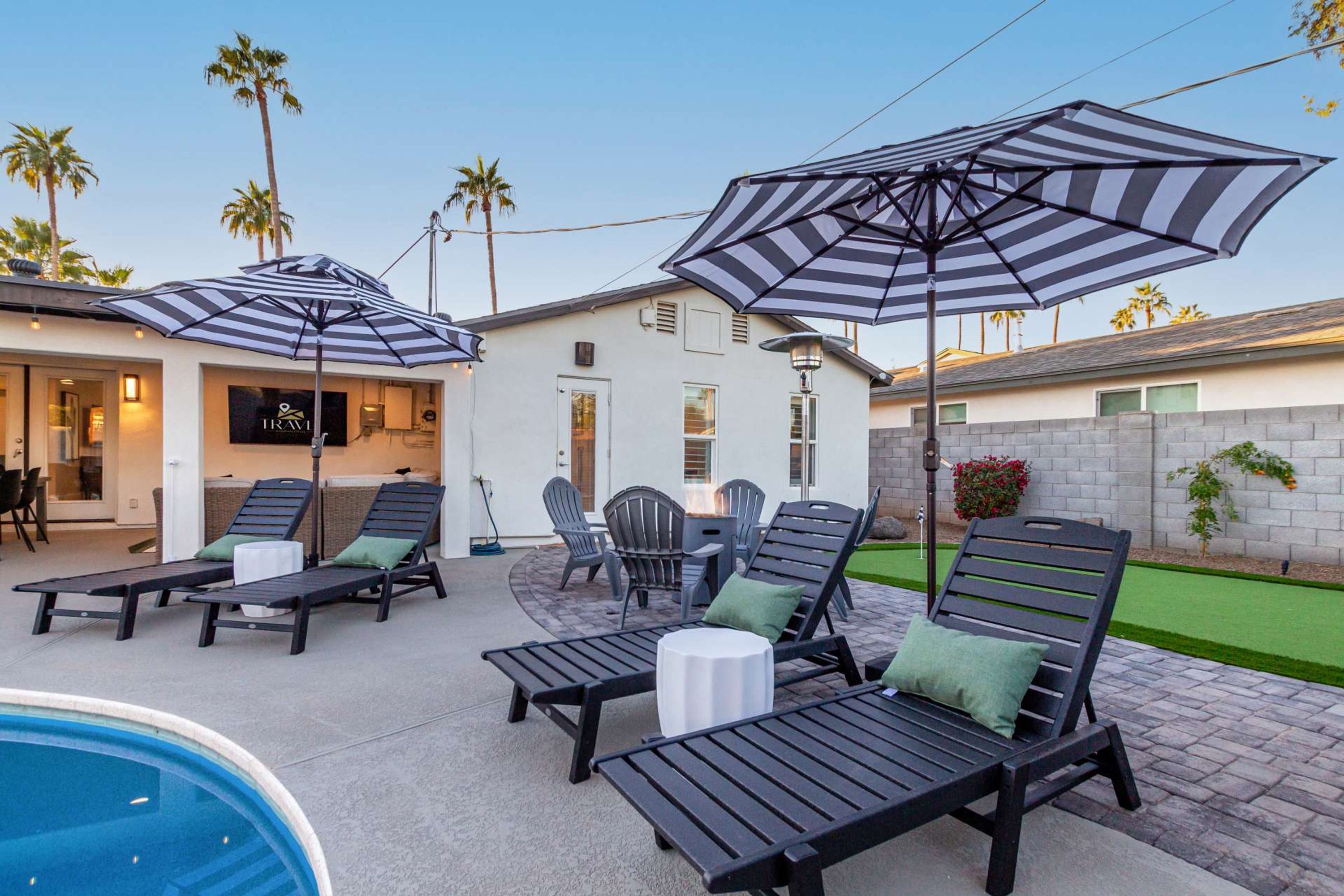 Un espace aménagé au bord de la piscine, avec des chaises longues, des parasols à rayures et une petite piscine.