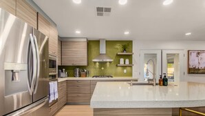 A modern kitchen with stainless steel appliances, wooden cabinetry, and a central island.