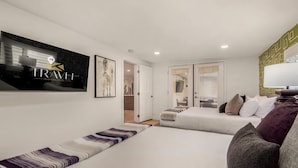 A hotel room with two beds, a large artwork on the wall, and a visible door leading to another room.