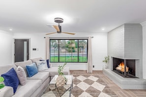 Relax in this stylish living room with a sofa, coffee table, and fireplace.
