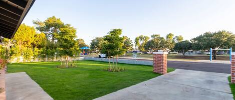 A well-maintained lawn with a brick pathway leading to a gated entrance.