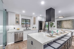 Enjoy cooking in this well-equipped kitchen with a central island, bar stools, and stainless steel appliances.