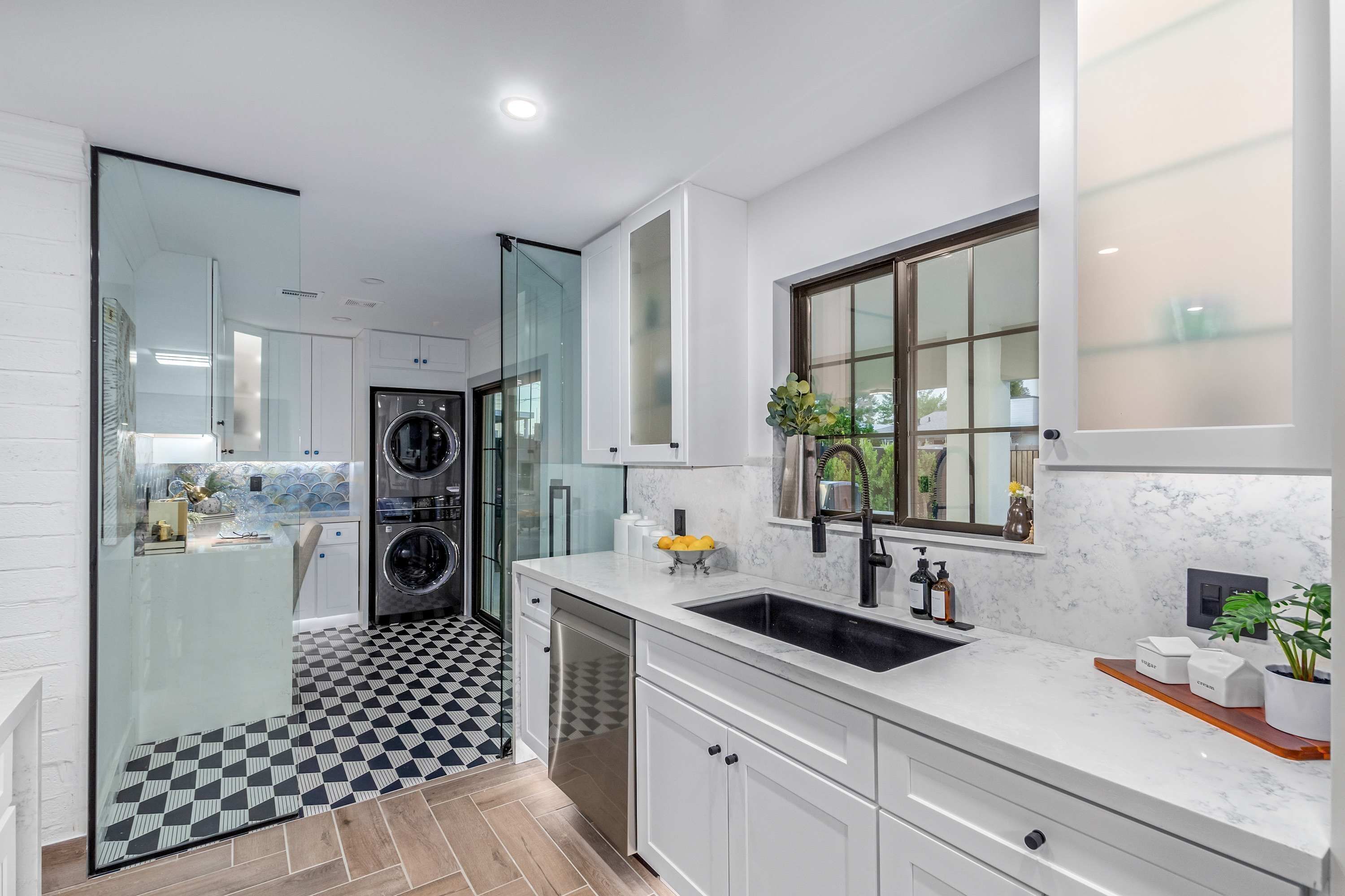 A modern kitchen with a built-in dishwasher, a large sink, and a window with a view.