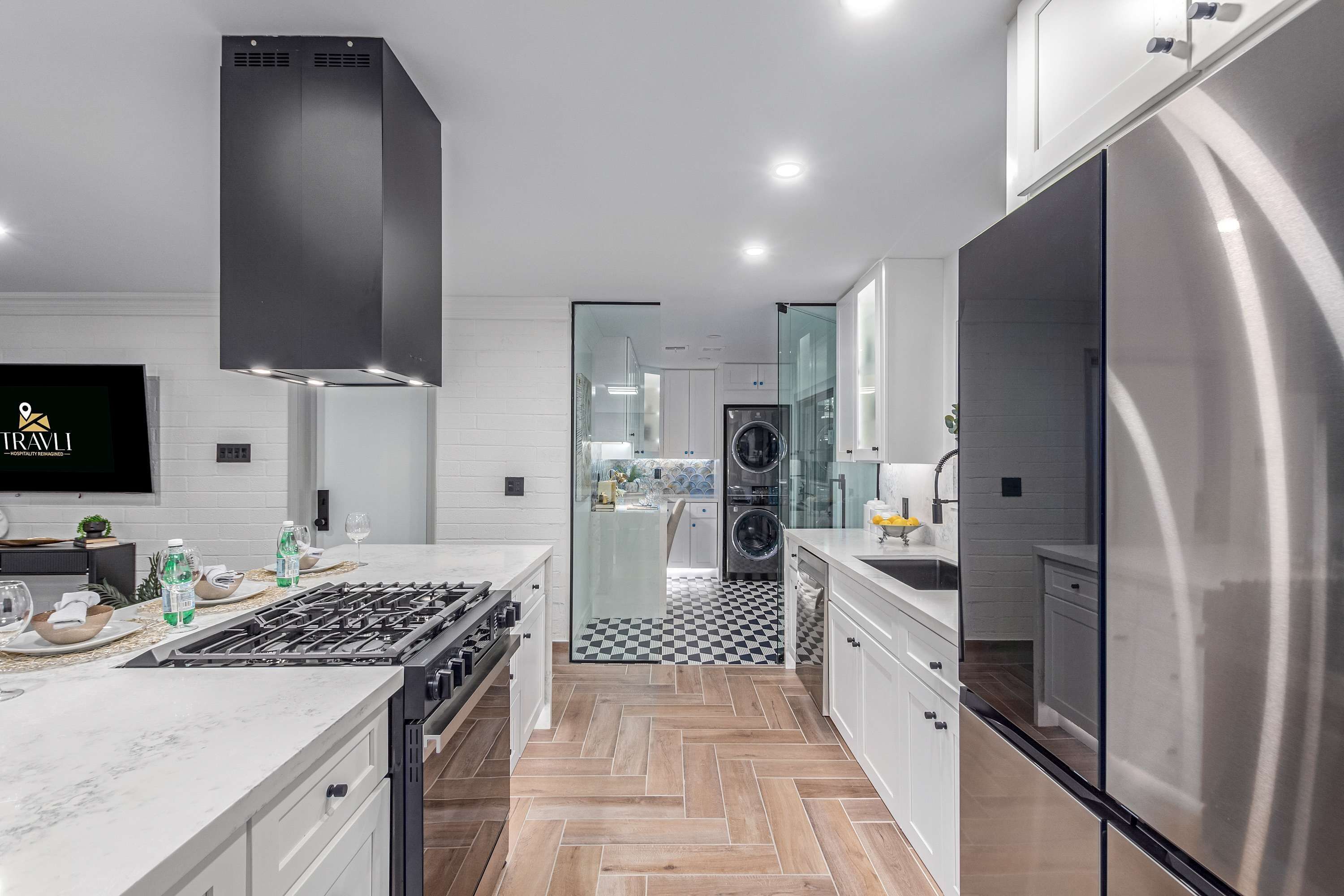Una cocina moderna con un refrigerador de acero inoxidable grande, un horno empotrado y una estufa a gas.