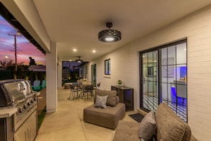 Enjoy al fresco dining and relaxation in this outdoor patio area, featuring a barbecue grill, seating area, and glass door leading to a covered patio.