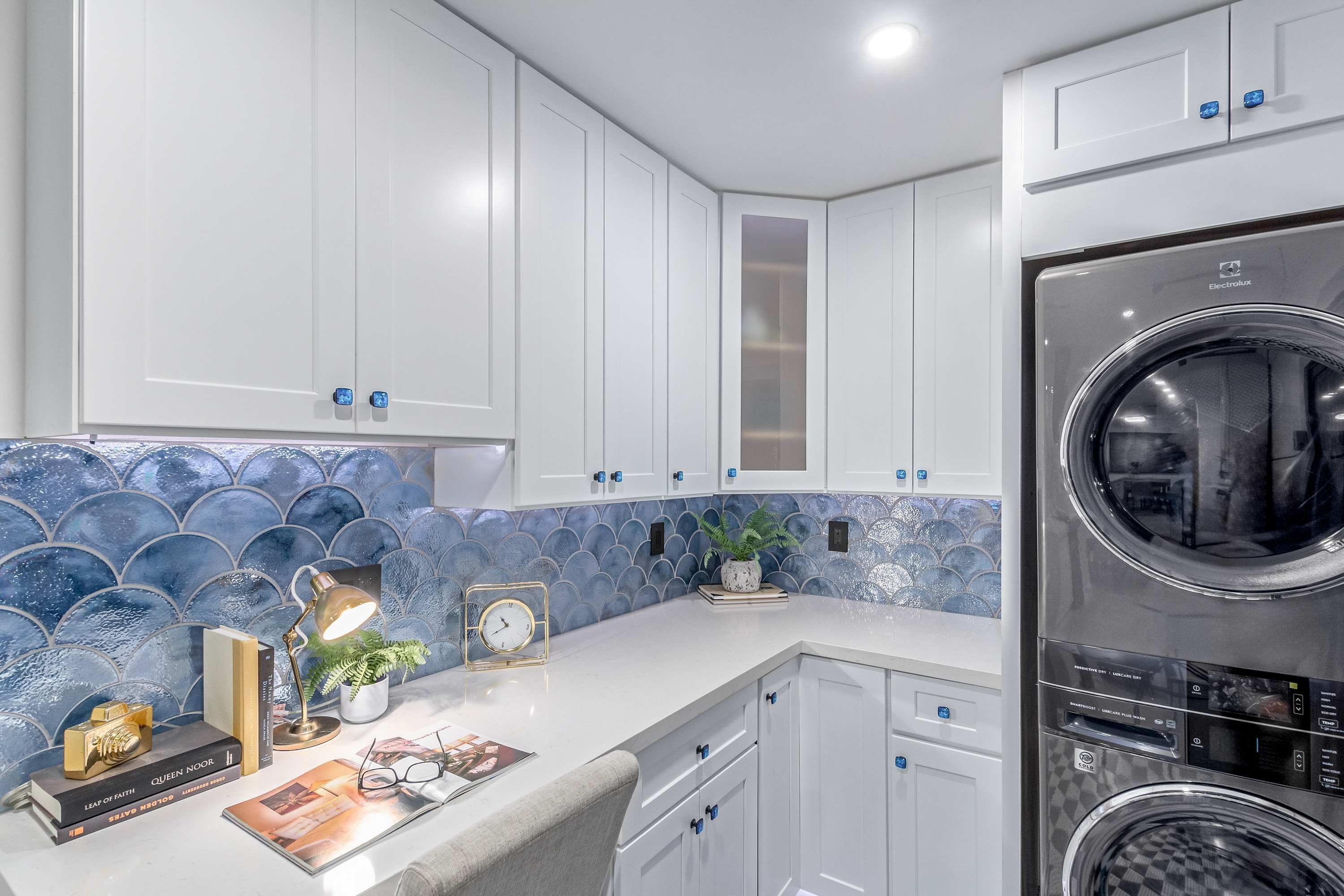 A modern kitchen with white cabinets, a stainless steel appliance, and decorative blue tiles.