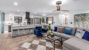 A modern kitchen with a central island, bar stools, and a dining area with a sofa and coffee table. - NEW Sundancer Oasis Old Town Pool Spa Rooftop Deck (Scottsdale)