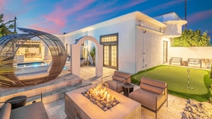 A modern outdoor patio with a fire pit, seating, and a well-maintained lawn.
