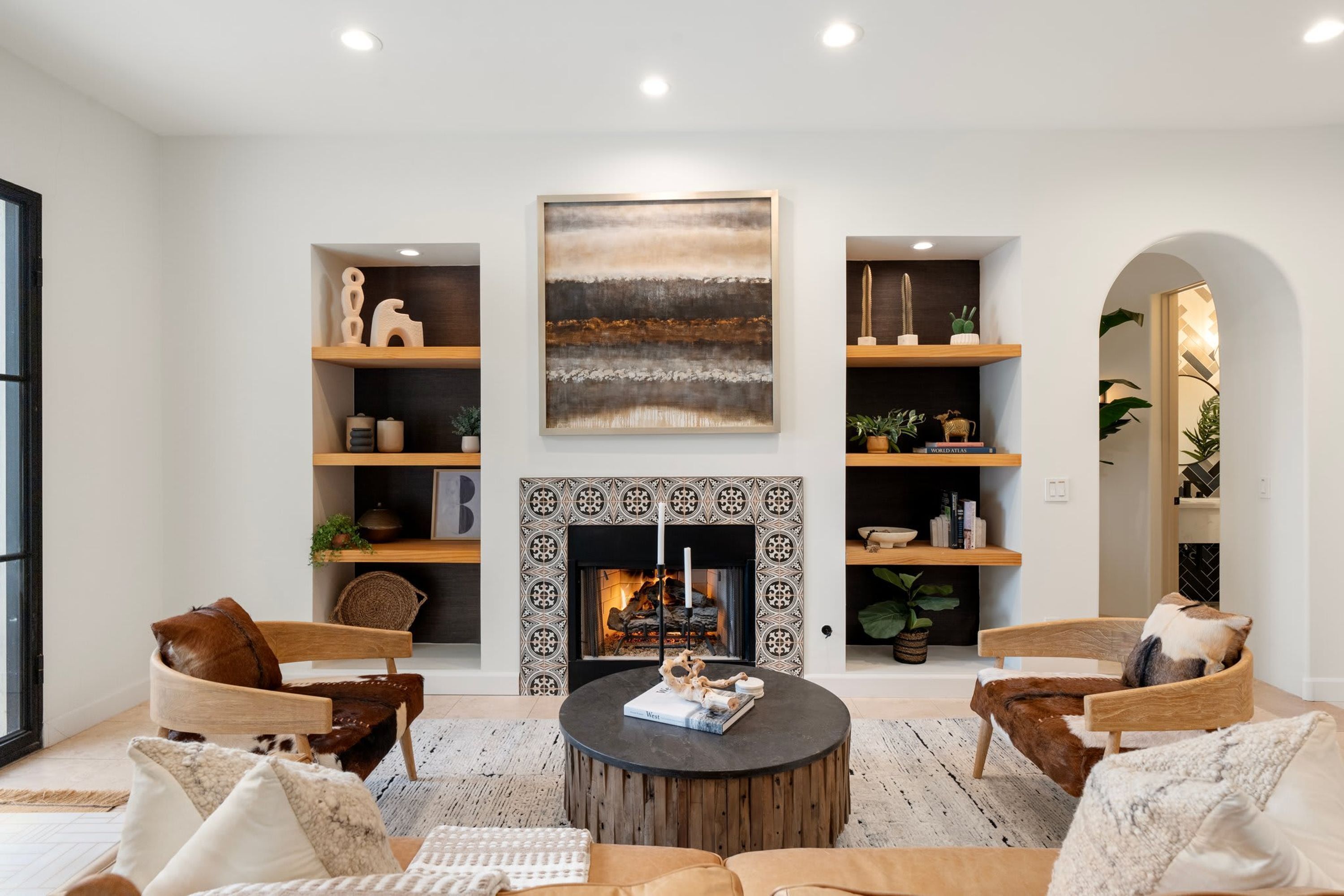 A modern living room with a fireplace, wooden shelves, and comfortable seating.