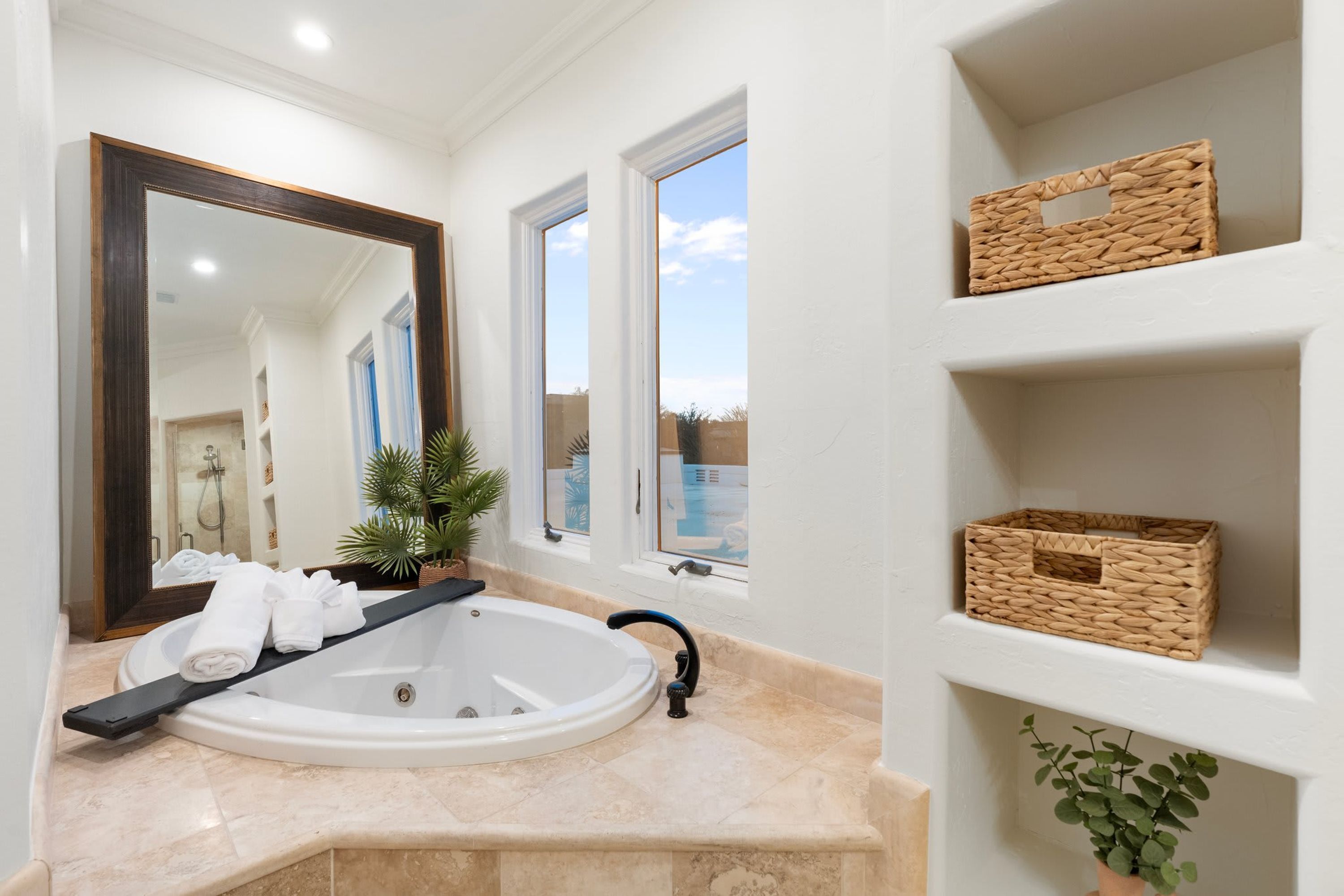 Une salle de bain moderne avec une baignoire, un grand miroir et une fenêtre.