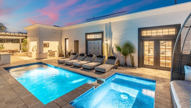 A modern outdoor pool area with lounge chairs and a patio.
