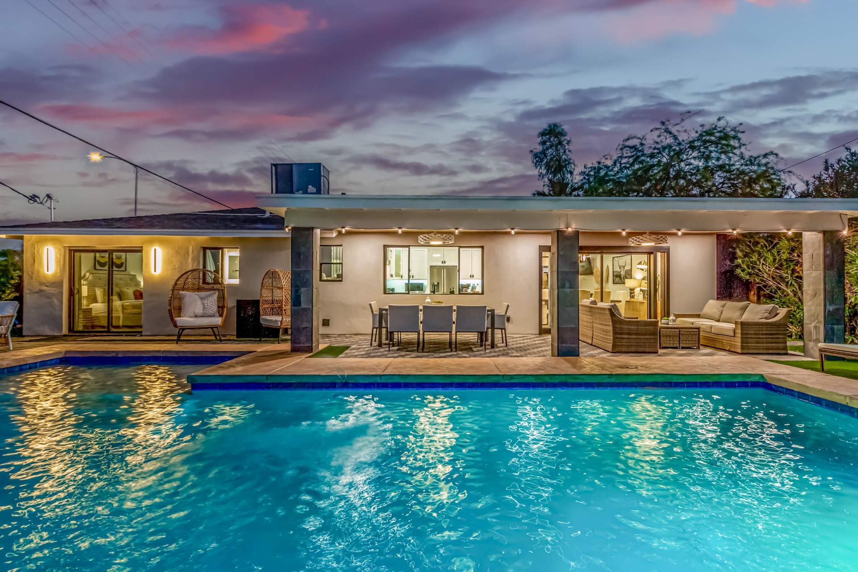A modern house with a swimming pool, outdoor seating, and a covered patio area.