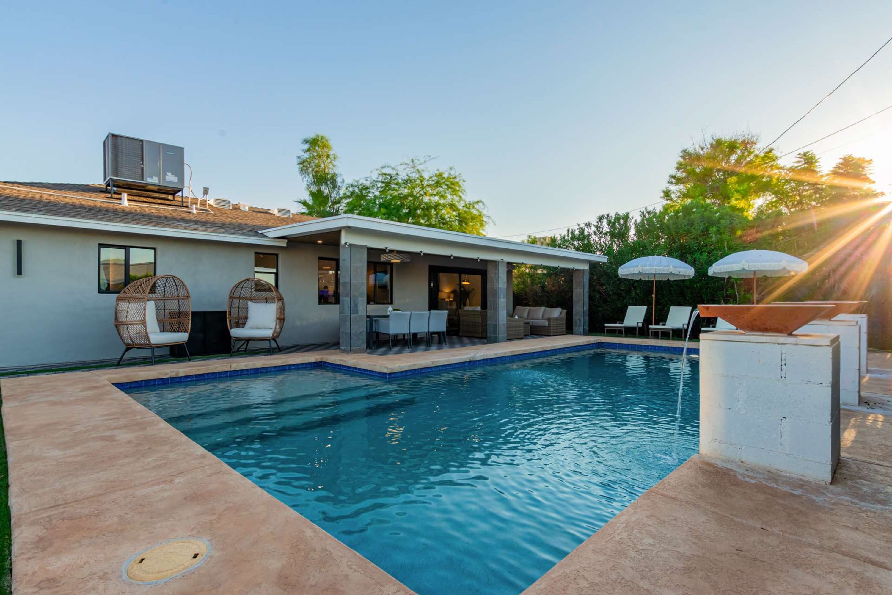A modern pool area with a rectangular pool, lounge chairs, and umbrellas.