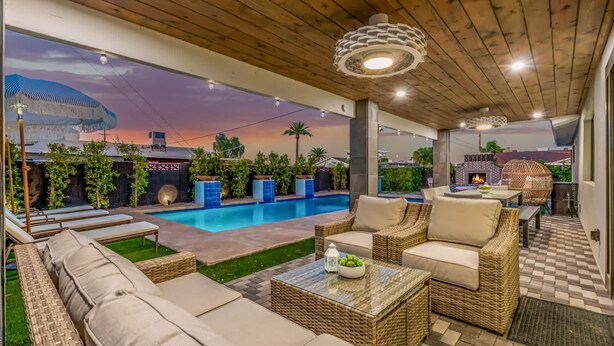A covered outdoor area with a pool, lounge chairs, and a seating area with a table and chairs. - NEW The Kensington Custom Pool Al-fresco Living (Scottsdale)