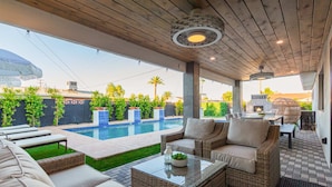 A covered outdoor patio with wicker furniture, a pool, and a view of the backyard. - NEW The Kensington Custom Pool Al-fresco Living (Scottsdale)