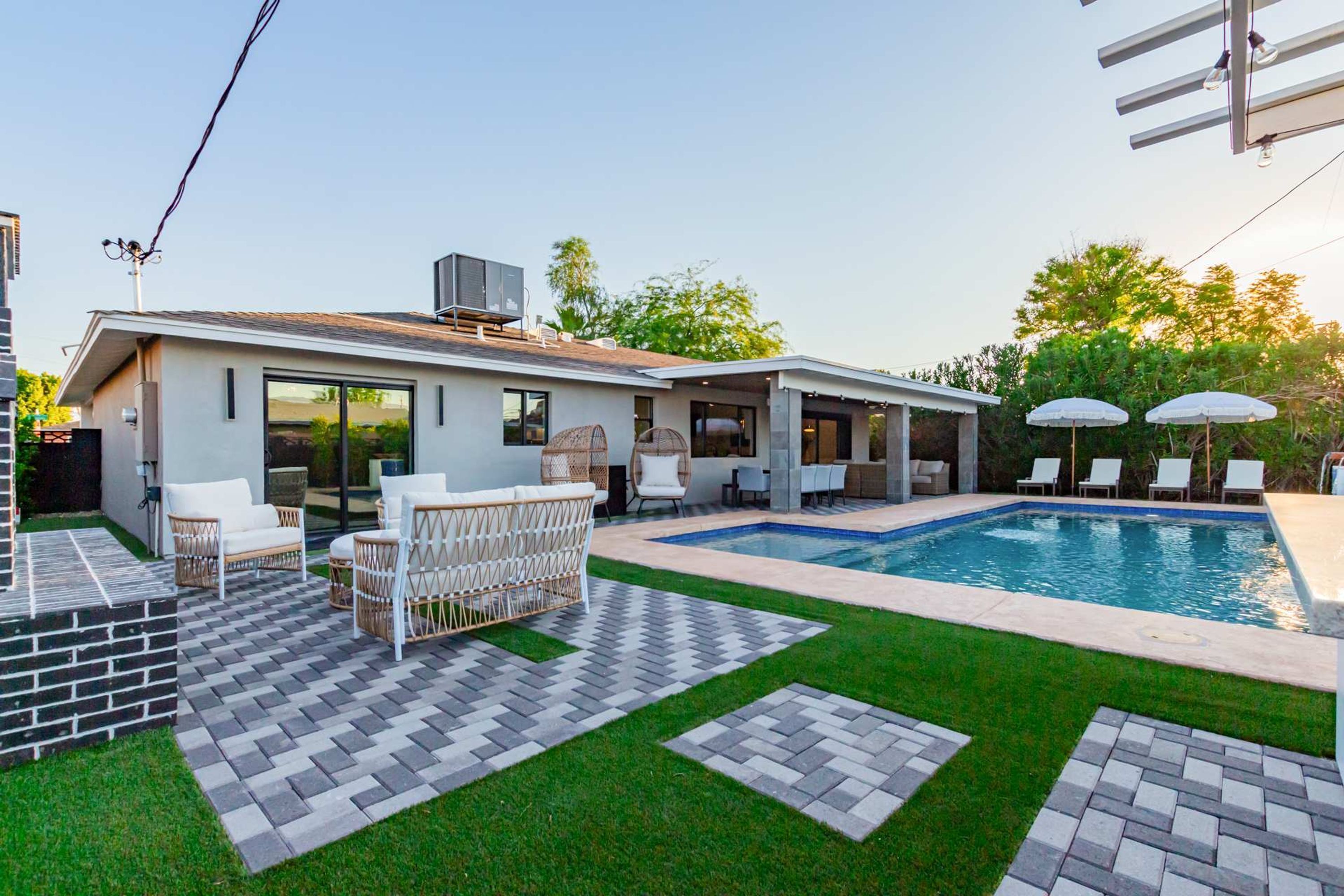 A modern house with a swimming pool, outdoor seating, and a well-maintained lawn.