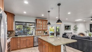 A modern kitchen with wooden cabinets, a granite countertop, and a built-in island. - NEW Parkwood Retreat w Pool Spa Kierland (Scottsdale)
