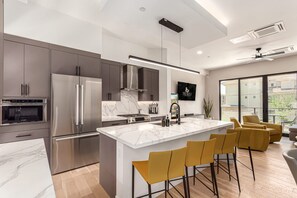 A modern kitchen with a central island, stainless steel appliances, and a large window offering a city view. - Papago Lux Townhouse 4level Oasis w Rooftop Lounge (Scottsdale)