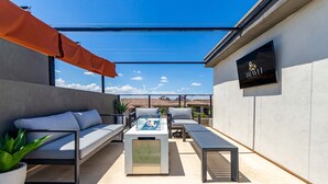 A modern outdoor patio with a sofa, lounge chairs, and a coffee table. - Papago Lux Townhouse 4level Oasis w Rooftop Lounge (Scottsdale)