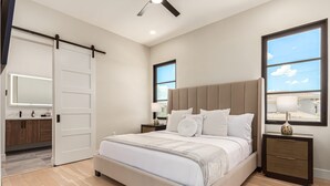 A bedroom with a large bed, a sliding door, a nightstand, a lamp, and a window with a view. - Papago Lux Townhouse 4level Oasis w Rooftop Lounge (Scottsdale)
