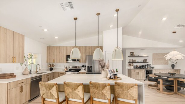 Una cocina moderna con una isla central, armarios de madera e iluminación colgante.