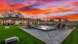 Un patio trasero con piscina, sillas de descanso y un césped cuidado.