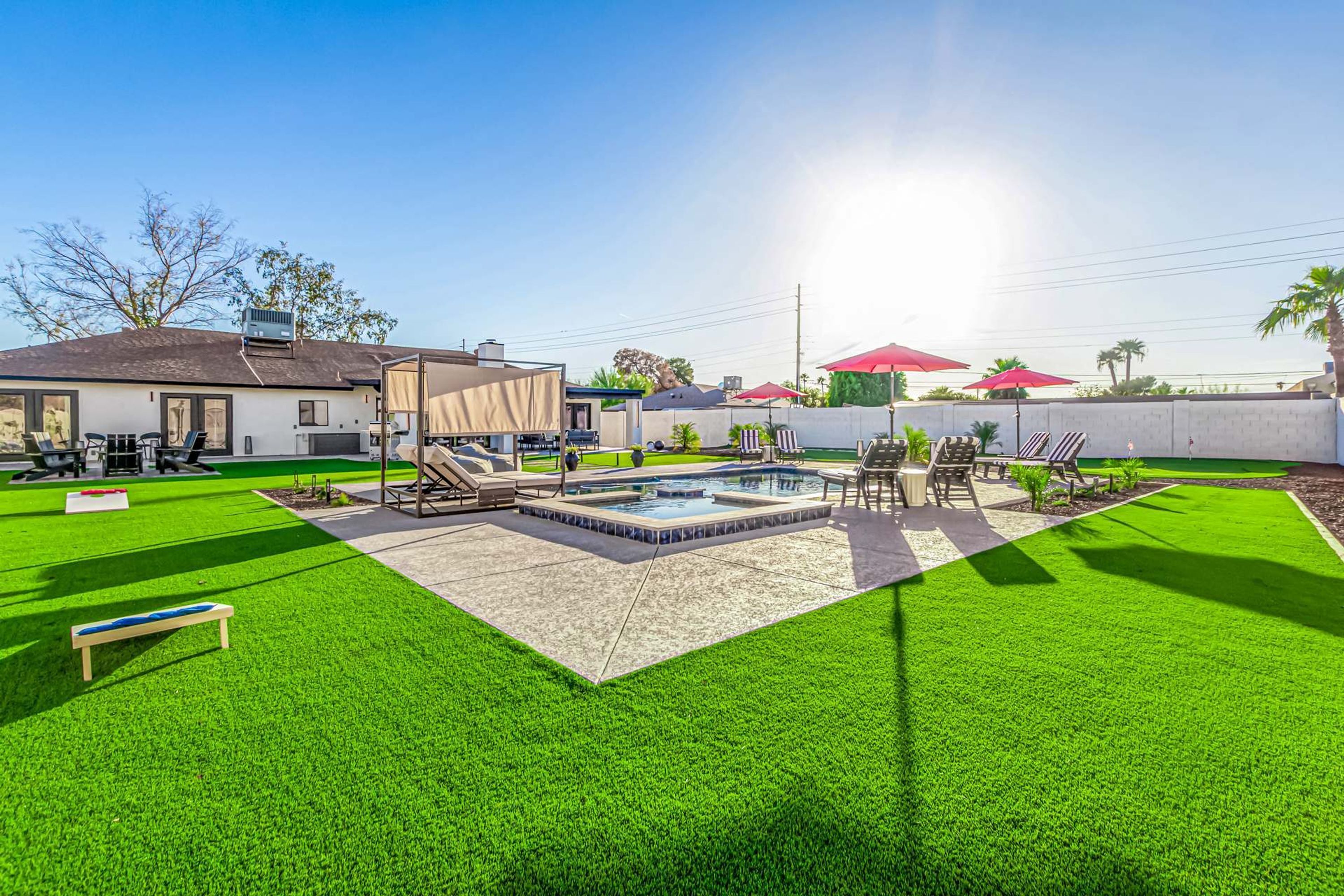 A backyard with a swimming pool, artificial grass, and outdoor furniture.