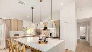 Una cocina moderna con una isla central, lámparas colgantes y armarios de madera.