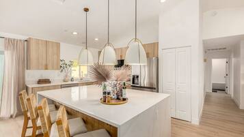 A modern kitchen with a central island, pendant lights, and wooden cabinetry.