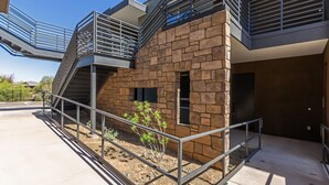 Un bâtiment moderne avec une façade en pierre, des garde-corps en m étal et un ciel dégagé.