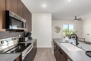 Una cocina moderna con electrodomésticos de acero inoxidable, una isla grande con pileta y un ventilador de techo.