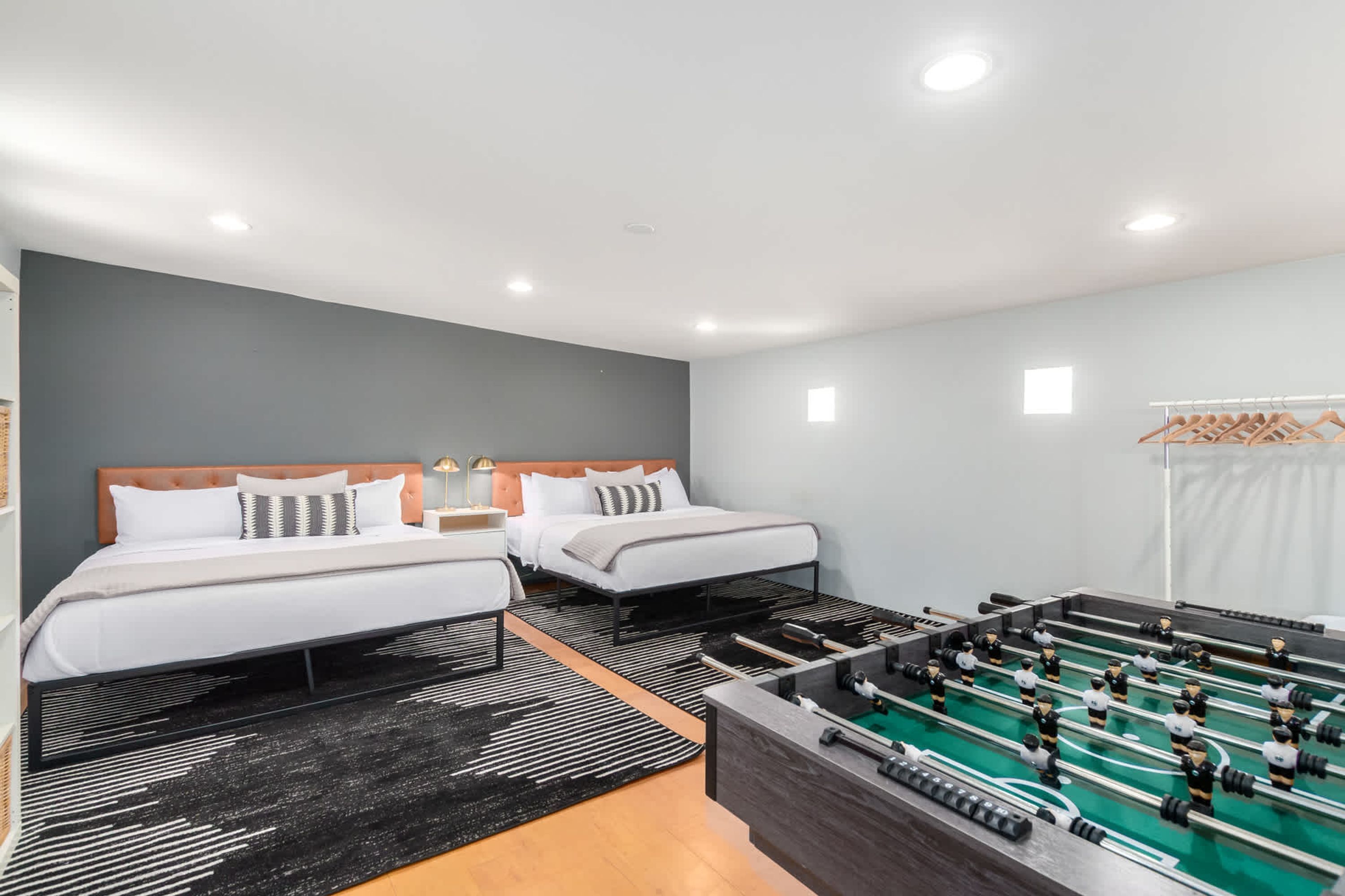 Une chambre d’hôtel avec deux lits, une table de baby-foot et une armoire.