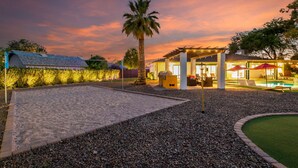 A pool area with a pergola, palm tree, and outdoor seating.