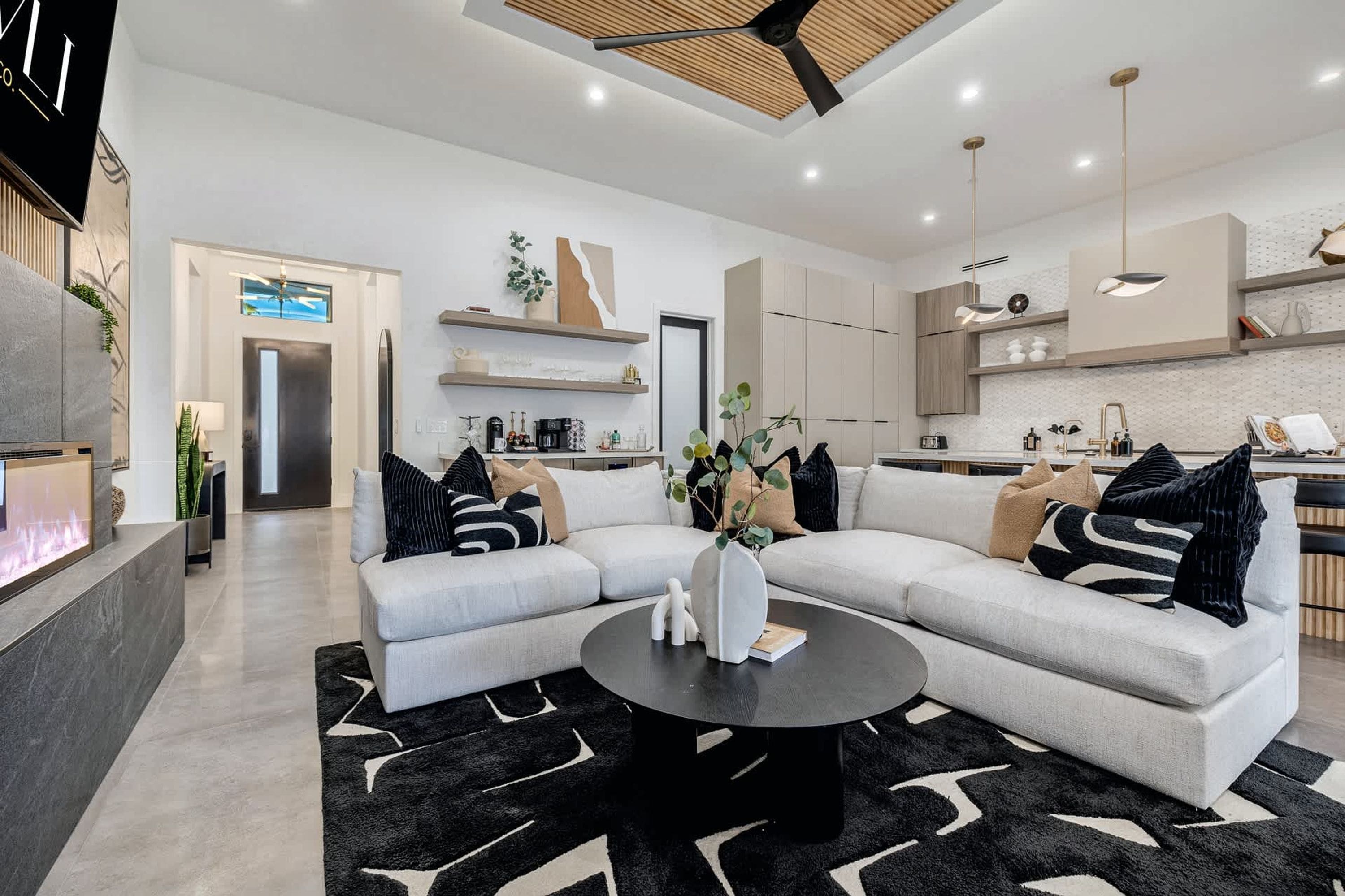 A modern living room with a sectional sofa, a coffee table, and a fireplace.