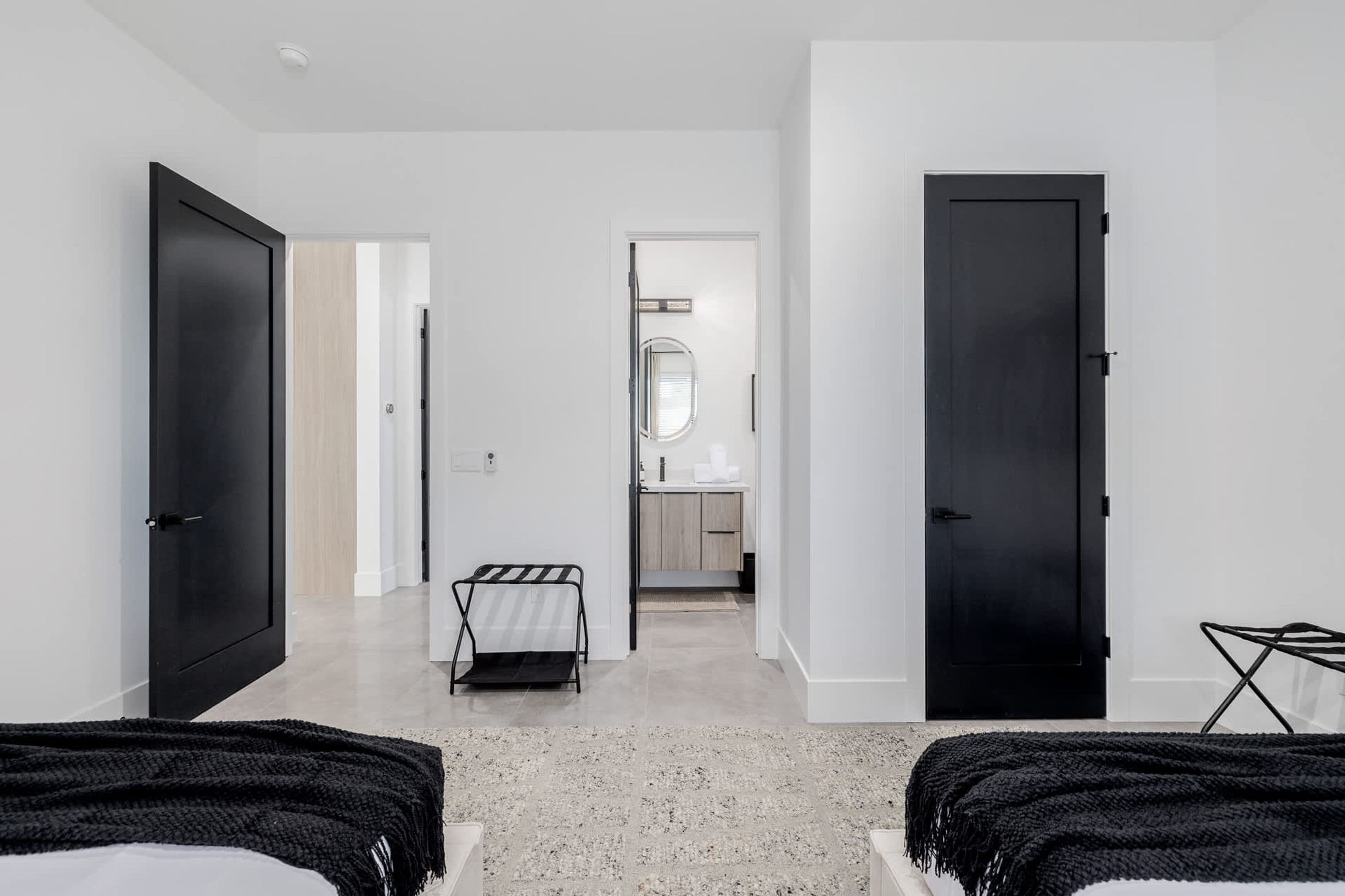 Une chambre d’hôtel moderne avec un grand lit, un petit coin salon et une salle de bain visible à travers une porte ouverte.