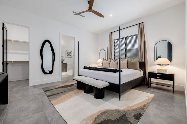 A modern bedroom with a bed, bedside tables, a ceiling fan, and a large mirror. - The Carlisle Experience 4 Showers Heated Pool (Scottsdale)