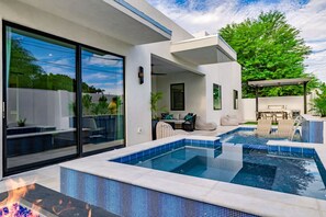 A modern outdoor pool area with a fire feature, a covered seating area, and a patio with outdoor furniture. - The Carlisle Experience 4 Showers Heated Pool (Scottsdale)