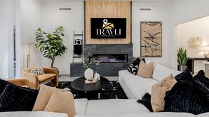 A modern living room with a fireplace, a mounted logo, and a minimalist design. - The Carlisle Experience 4 Showers Heated Pool (Scottsdale)