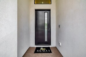 A modern entrance with a dark door, a doormat, and a light-colored wall. - The Carlisle Experience 4 Showers Heated Pool (Scottsdale)
