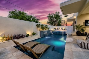 A modern outdoor pool area with lounge chairs, a bar, and a waterfall feature. - The Carlisle Experience 4 Showers Heated Pool (Scottsdale)
