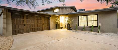 A modern house with a garage, a driveway, and a large window.
