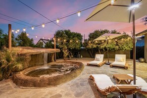 A serene outdoor setting with a hot tub, lounge chairs, and string lights against a twilight sky. - Solanova Designer Oasis With Cocktail Pool Theater (Scottsdale)