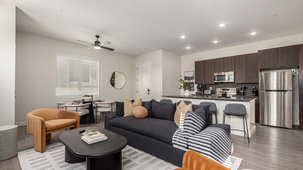 A modern living room with a sofa, coffee table, and armchairs. It features a kitchen with a refrigerator, microwave, and island. - Macallister 1006 Close to Golf Mayo Heated Pool (Scottsdale)
