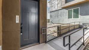 A modern building entrance with a dark door, a metal handrail, and a concrete staircase leading to a higher level. - Macallister 1006 Close to Golf Mayo Heated Pool (Scottsdale)